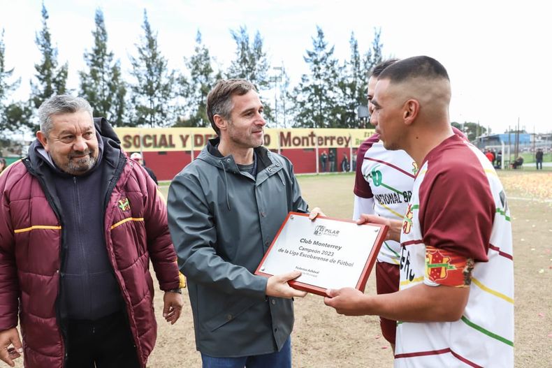 PLACA AL CAMPEÓN. Achával entregó un reconocimiento al capitán de Monterrey, Andrés Llanos, por el título logrado en el Campeonato B y el ascenso a la máxima categoría de la Liga Escobarense. Acompañaron en la previa al partido con Los Altos, el dirigente Chiqui Modón y el jugador Ezequiel García (6).