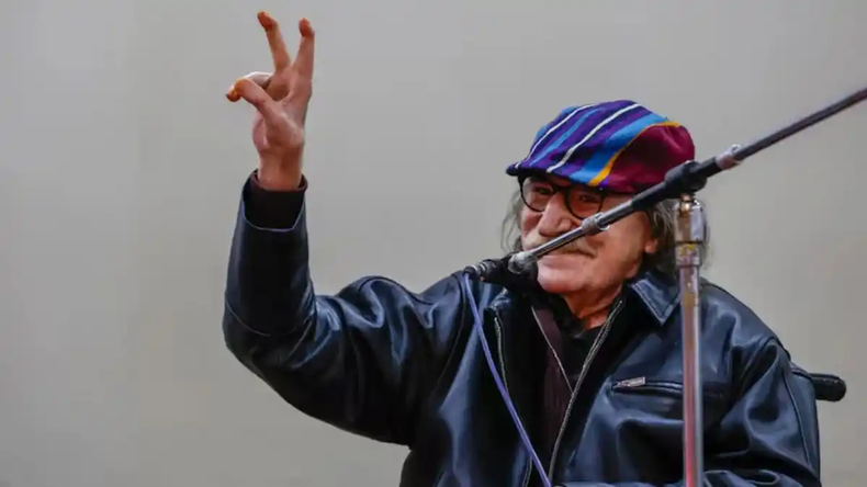 Charly García levantando los dedos en V durante la ceremonia. (UBA).