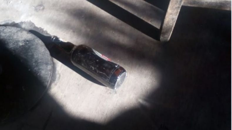 La botella cargada de alcohol quedó tirada en el suelo..