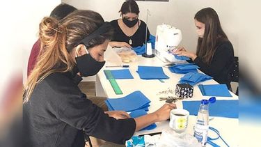 MANOS A LA OBRA. Integrantes de la agrupación, confeccionando los barbijos..