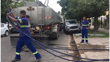 MANGUERA. Empleados de Aysa cargando un tanque de agua, ayer a la tarde, en Villa Morra..