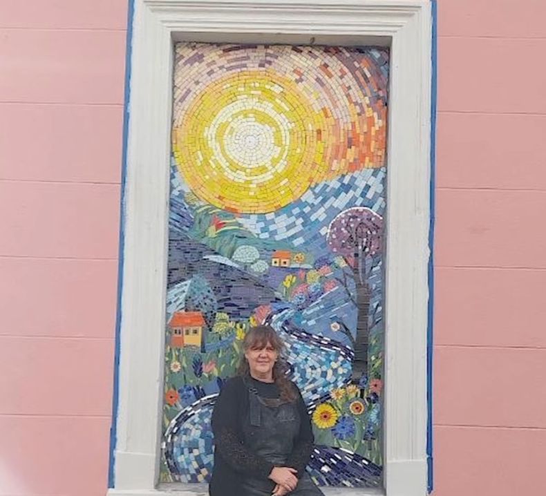 Silvia Kuhn en el mosaico que embellece la fachada de la antigua propiedad donde montará su taller.