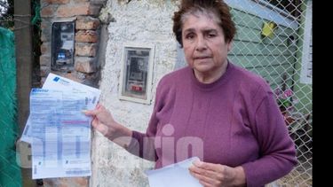En la puerta de su casa, Mercedes muestra la factura de 3.700 pesos que aún debe..