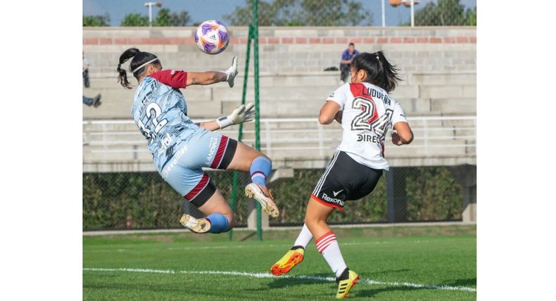 COMO DELANTERA. Ludueña define por sobre la arquera de Lanús.