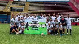 El plantel de Real con la bandera que tenía la leyenda dedicada a Campe: “Fuiste más que un DT”..