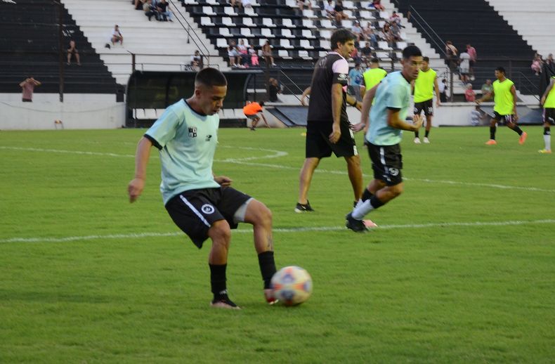 PELOTA. Axel Paiva toca de primera. Detrás Mathías Crocco.