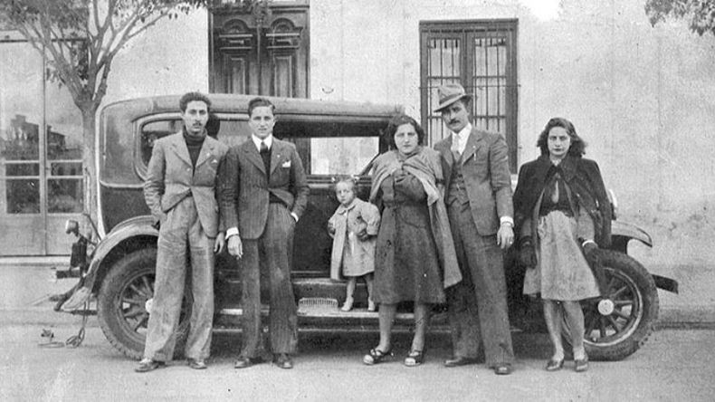 Fiestas Patronales de 1943. Los vecinos posan sobre la calle Rivadavia, donde los autos estacionados eran escenarios comunes para las fotos de la época..