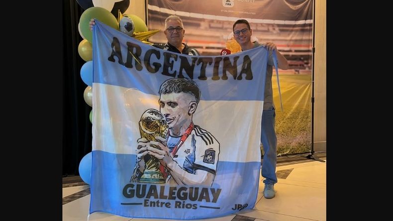 Raúl Martínez junto al cronista de Canal 9 de Gualeguay, posando con la bandera de Lisandro Martínez hecha por José Pignotti.