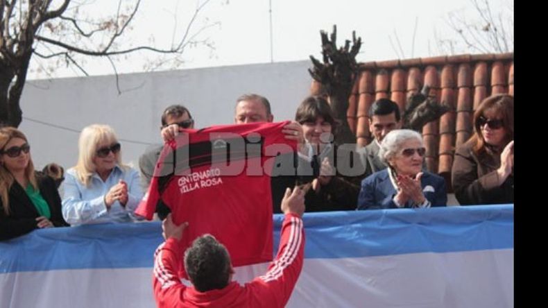 En pleno desfile, el intendente Zúccaro recibe una camiseta del Deportivo Villa Rosa de manos de un integrante del equipo..