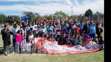Todo el barrio unido. Los jugadores e hinchas de Agustoni posan con el trofeo de campeón..