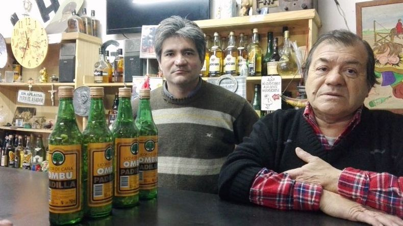 Cándido y Tito, al frente de el bar El Laucha, con la tradicional preparación de caña con ruda..