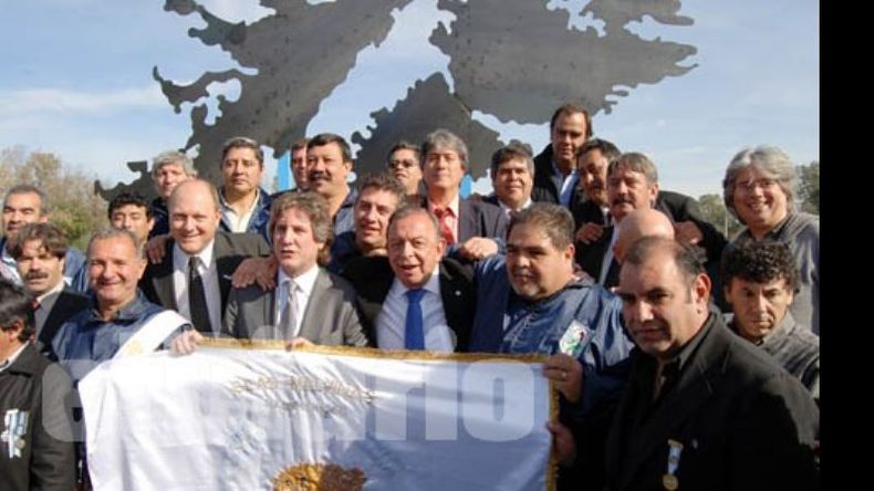 Boudou y Zúccaro rodeados por los ex combatientes. De fondo, el monumento construido por Alejandro Marmo..