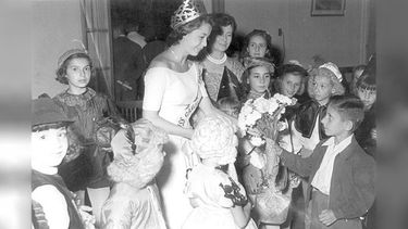 Un niño le entrega un ramo de claves blancos a Gladys Libertaria Costabel, Reina del Carnaval de 1957. .