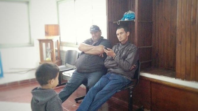 José, el vecino que amenazó con encadenarse, dialoga por teléfono con el responsable de la delegación. A su lado, el jefe de cuadrilla que ofició de intermediario..