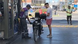 ASÍ, SÍ. Un motociclista carga combustible con su correspondiente casco..
