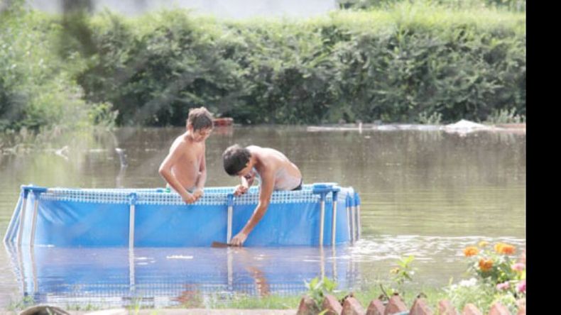 Agua y más agua. Chicos en una pilata, en su casa inundada de Los Grillos..