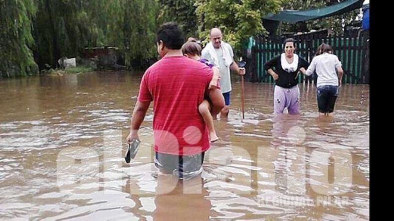 Vecinos de Villa Verde, ayer, tratando de desplazarse por las calles del barrio. Hubo más de un metro de agua en las casas..