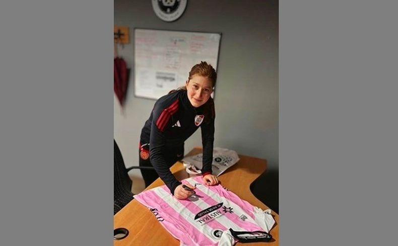 Annika Paz a punto de firmar la camiseta de Las Reinas que quedará en el club.