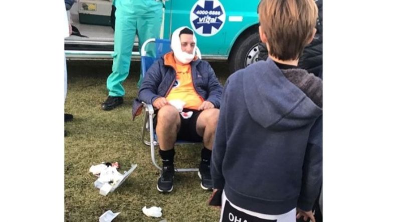 El árbitro agredido con el maxilar fracturado esperando la atención médica..